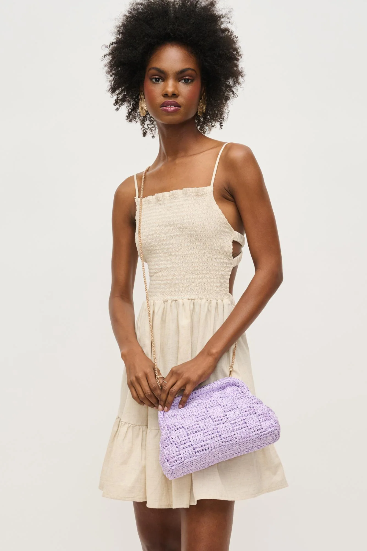 Woman holding a purple clutch bag against a plain background