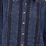 A close-up of a dark blue denim button-up shirt with vertical eyelet lace panels on the front, worn by a model whose blonde hair is visible at the collar.