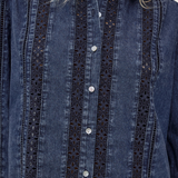 A close-up of a dark blue denim button-up shirt with vertical eyelet lace panels on the front, worn by a model whose blonde hair is visible at the collar.