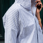 Person wearing a blue and white striped shirt with a blurred background