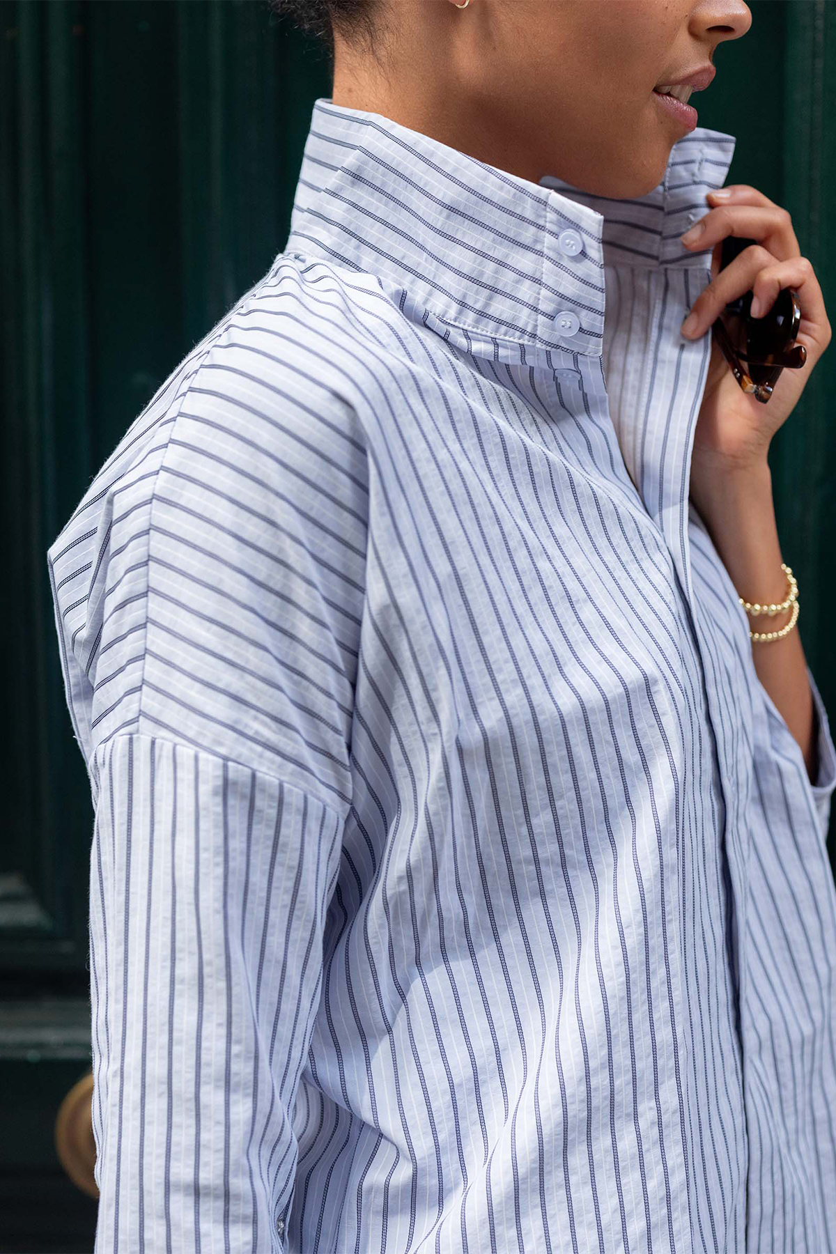 Person wearing a blue and white striped shirt with a blurred background