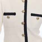 close up on woman in white jacket with black trim and gold buttons 