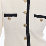 close up on woman in white jacket with black trim and gold buttons 