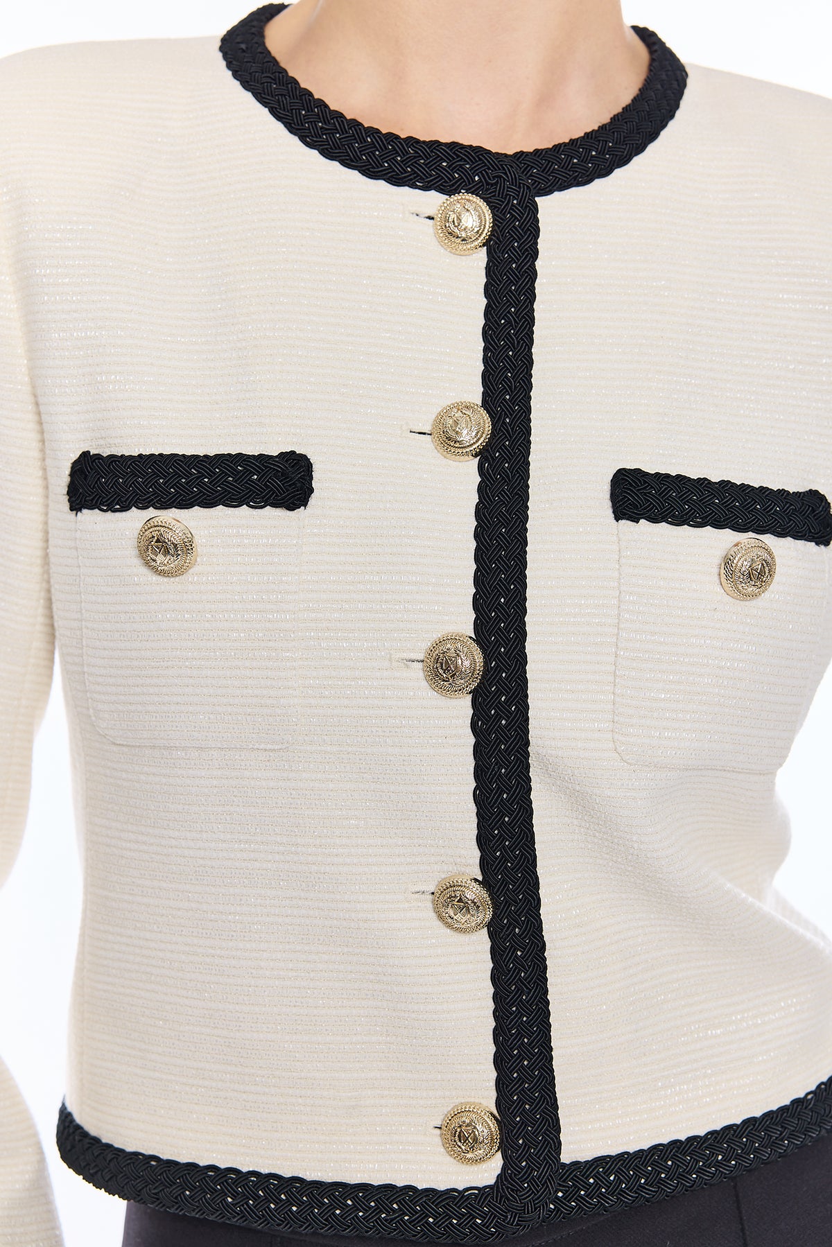 close up on woman in white jacket with black trim and gold buttons 