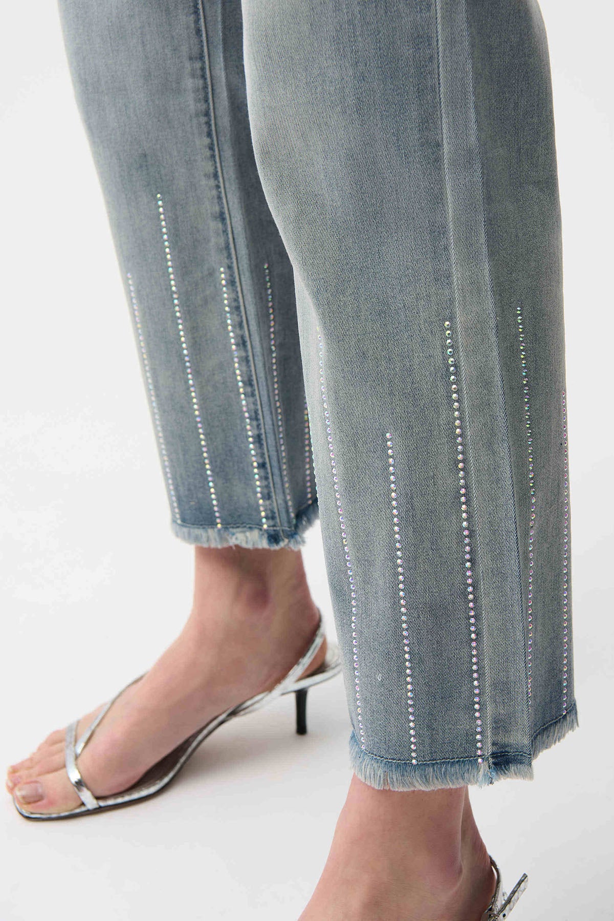 Close-up of light blue jeans with decorative stitching on a white background