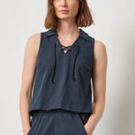 Woman wearing a navy sleeveless top and pants against a plain background