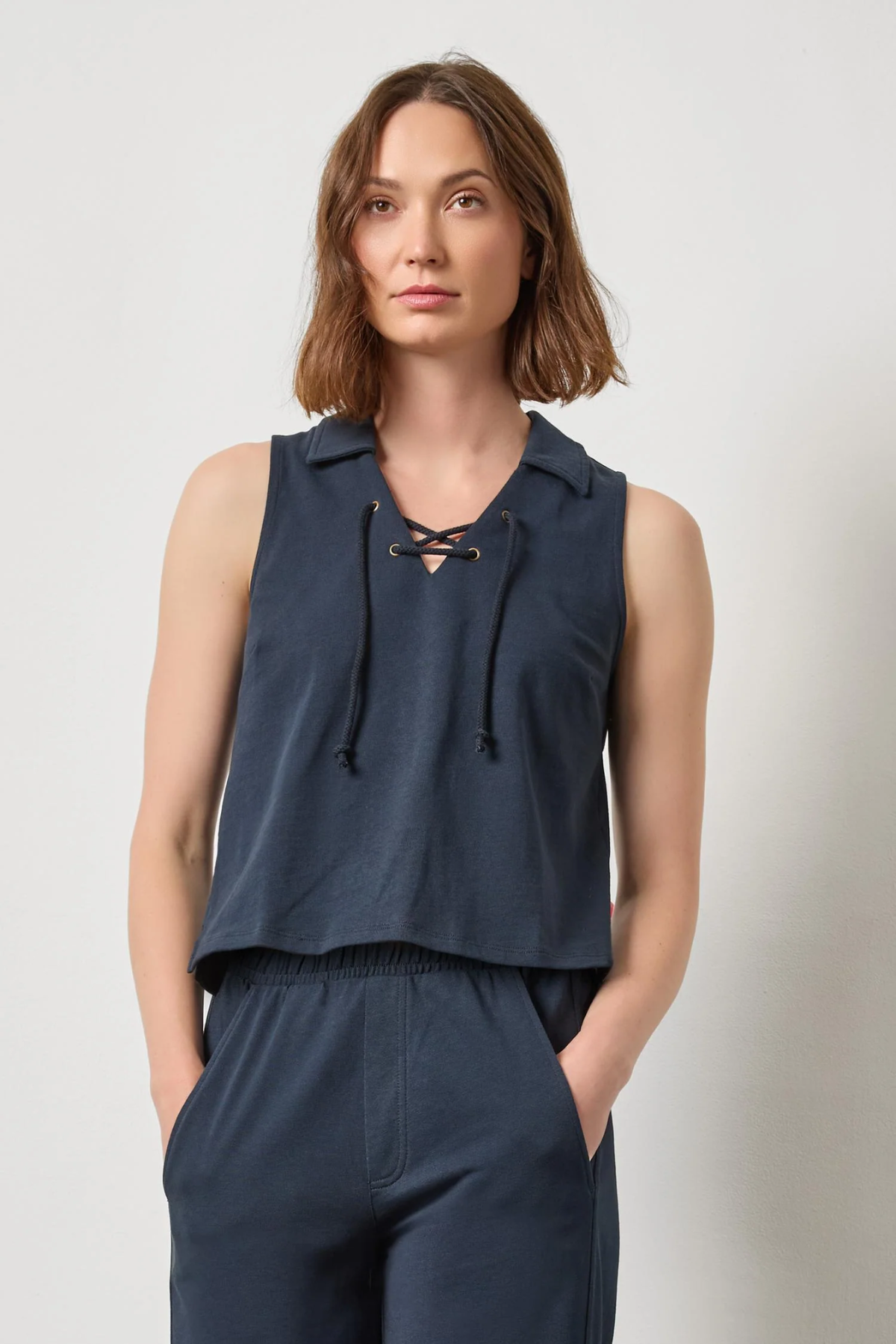 Woman wearing a navy sleeveless top and pants against a plain background