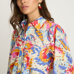 Woman wearing a colorful patterned shirt against a white background