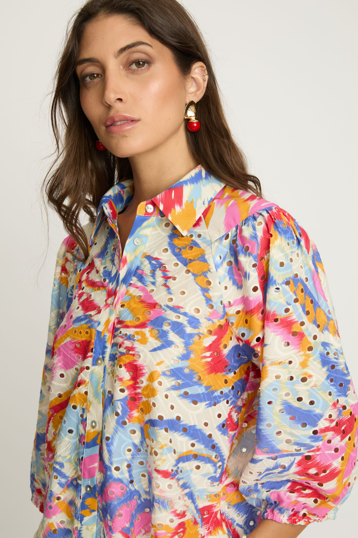 Woman wearing a colorful patterned shirt against a white background