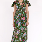 A model wearing a green midi dress with a colorful floral and bird print, featuring flutter sleeves and a tie-waist detail, set against a plain white studio background.