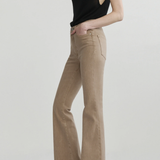 A model wearing beige flared jeans and a black sleeveless top, standing against a light gray studio background.