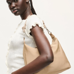 Woman holding a beige handbag against a white background