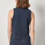 Person wearing a navy sleeveless top and pants on a light gray background