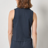 Person wearing a navy sleeveless top and pants on a light gray background