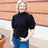 Knit sweater with puff sleeves and pom pom texture, styled with denim.