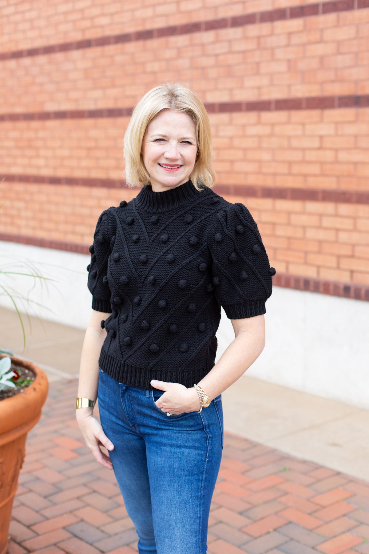 Knit sweater with puff sleeves and pom pom texture, styled with denim.