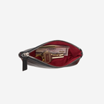 A dark brown leather zippered pouch shown open, revealing a deep red velvet-lined interior with various items inside, set against a plain light gray background.