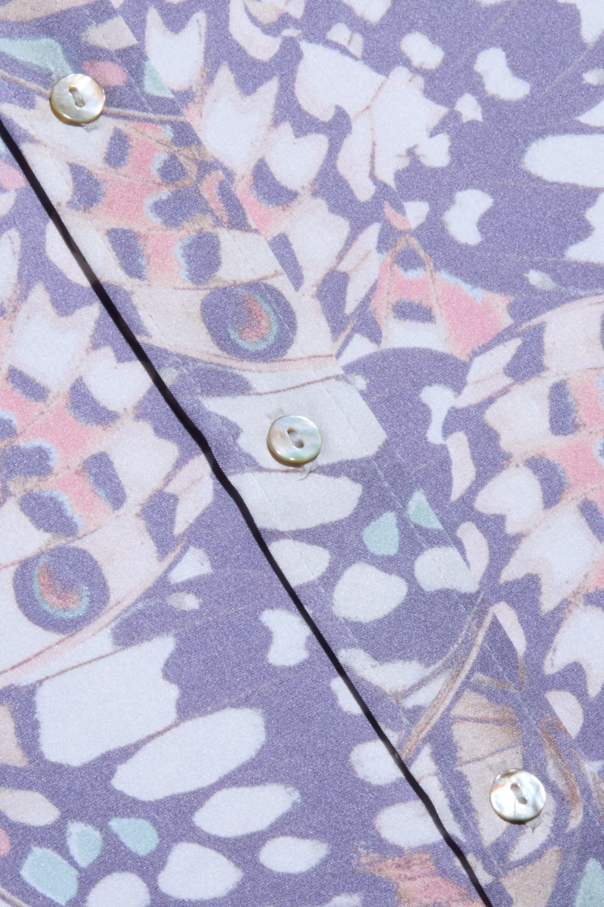 Close-up of a shirt with a butterfly pattern and buttons on a purple background