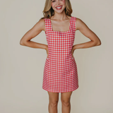 Woman wearing a red and white checkered dress against a beige background