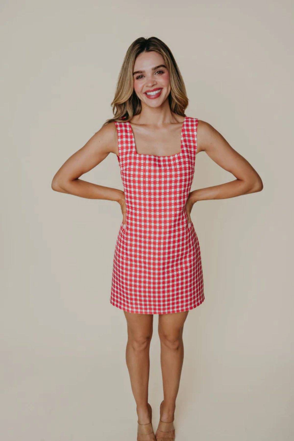 Woman wearing a red and white checkered dress against a beige background