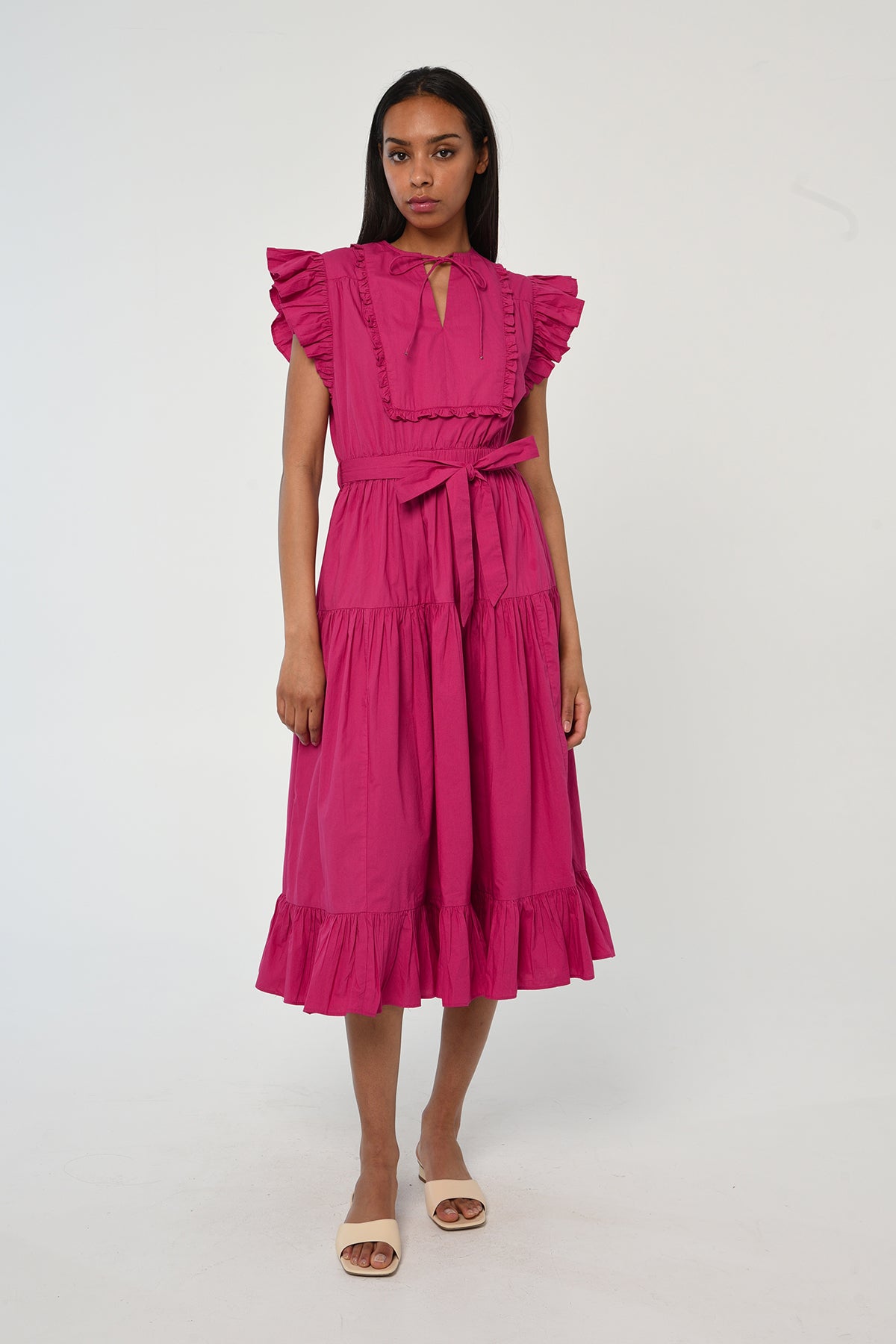 Woman wearing a vibrant pink sleeveless midi dress with soft tailoring and fluid drape.