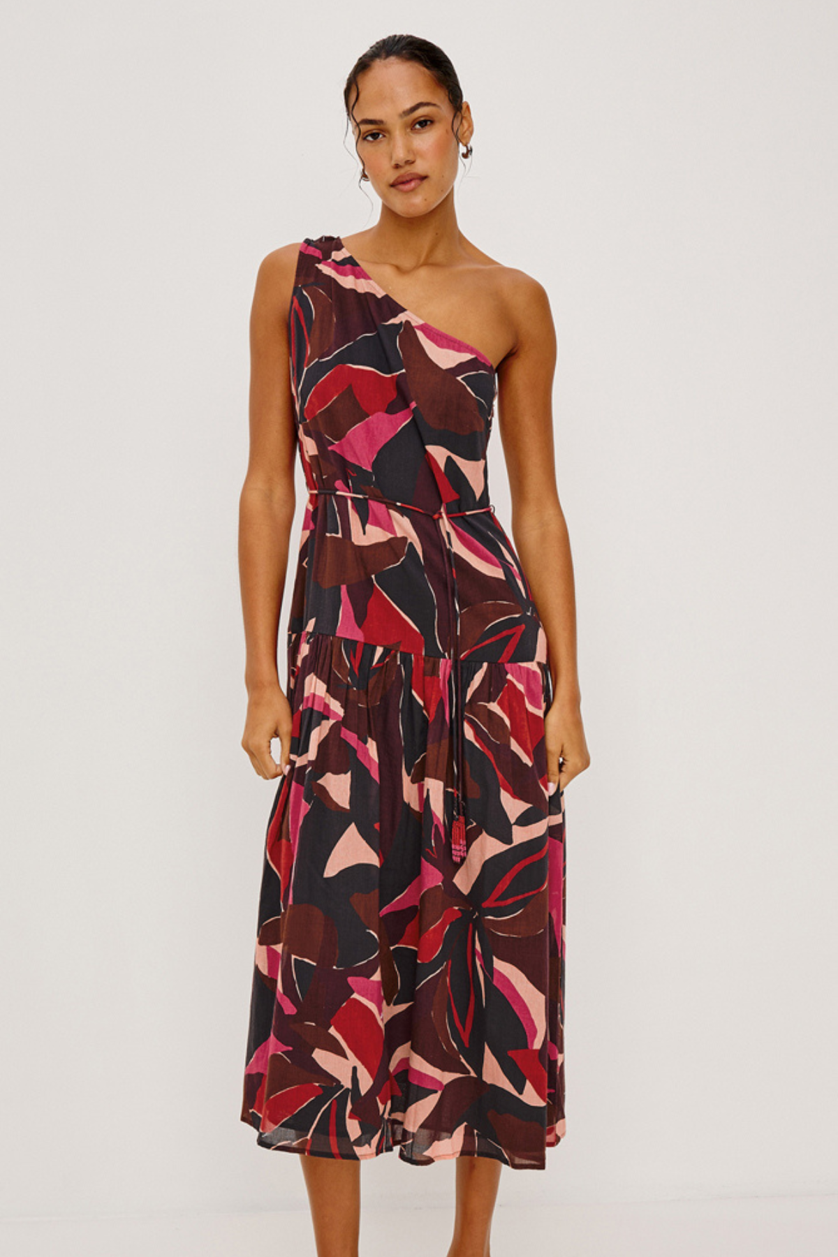 Woman wearing a one-shoulder patterned dress on a plain background