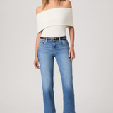 Woman wearing a white off-shoulder top and blue jeans on a white background