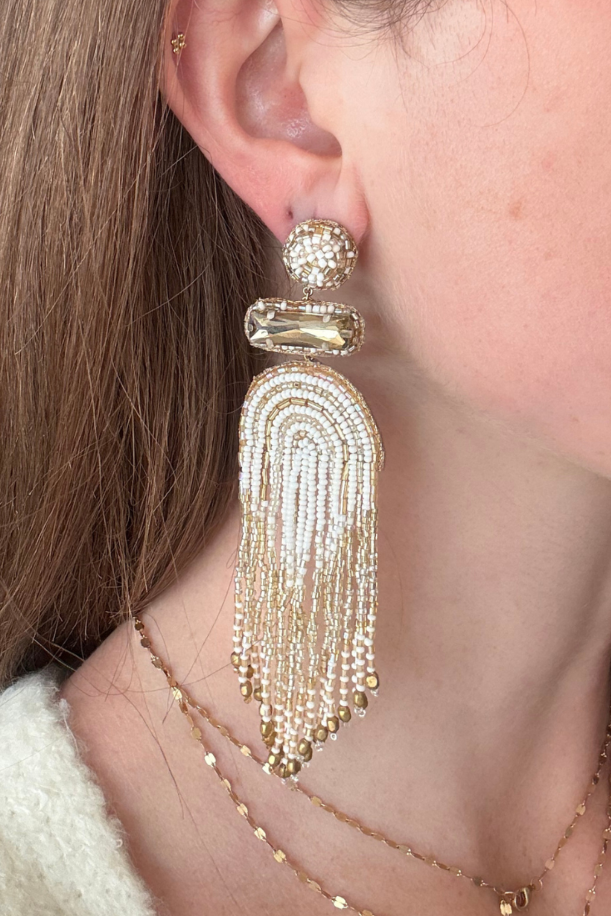 Model wearing gold beaded and chain detail drop earrings. 