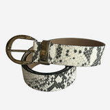 A snakeskin-patterned leather belt with a black and white python print and a bronze-tone metal buckle, coiled on a light gray background.