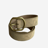 A light beige suede belt with a prominent gold-tone metal buckle, coiled on a plain light gray background.