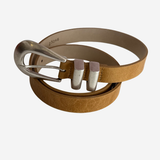A tan leather belt with a textured finish and a silver-tone metal buckle, coiled on a light gray background.