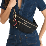 Black crossbody bag on model wearing a denim jumpsuit on white background.