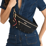 Black crossbody bag on model wearing a denim jumpsuit on white background.
