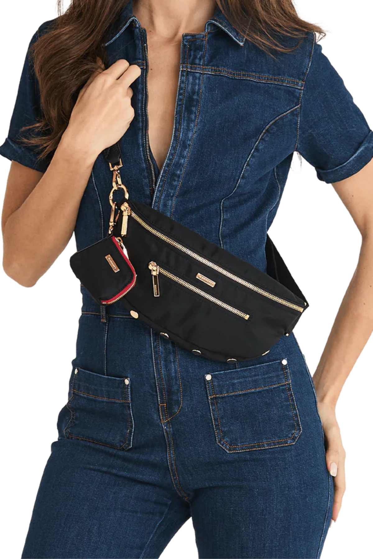 Black crossbody bag on model wearing a denim jumpsuit on white background.