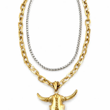 A two-tone necklace featuring a thick gold curb chain and a thinner silver box chain, both adorned with a polished gold bull skull pendant.