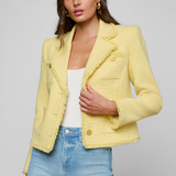 Woman wearing a yellow jacket and blue jeans on a gray background