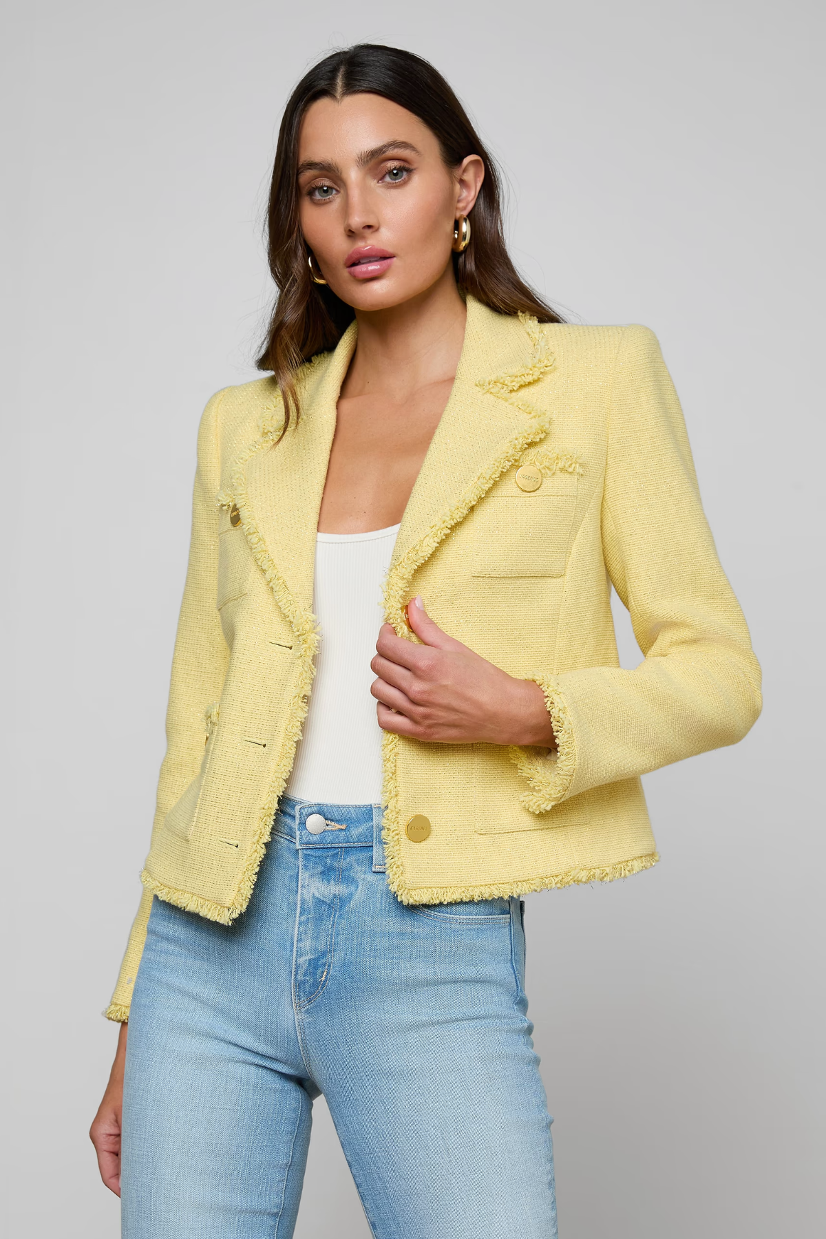 Woman wearing a yellow jacket and blue jeans on a gray background