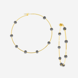Gold hoops with dark gray beads on a light gray background.