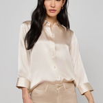 Woman wearing a beige satin shirt and pants on a plain background