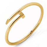 A polished gold-tone open cuff bangle bracelet with a geometric, stylized bar design, shown on a clean white background.