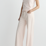 Person wearing a light pink t-shirt and wide-leg pants on a white background