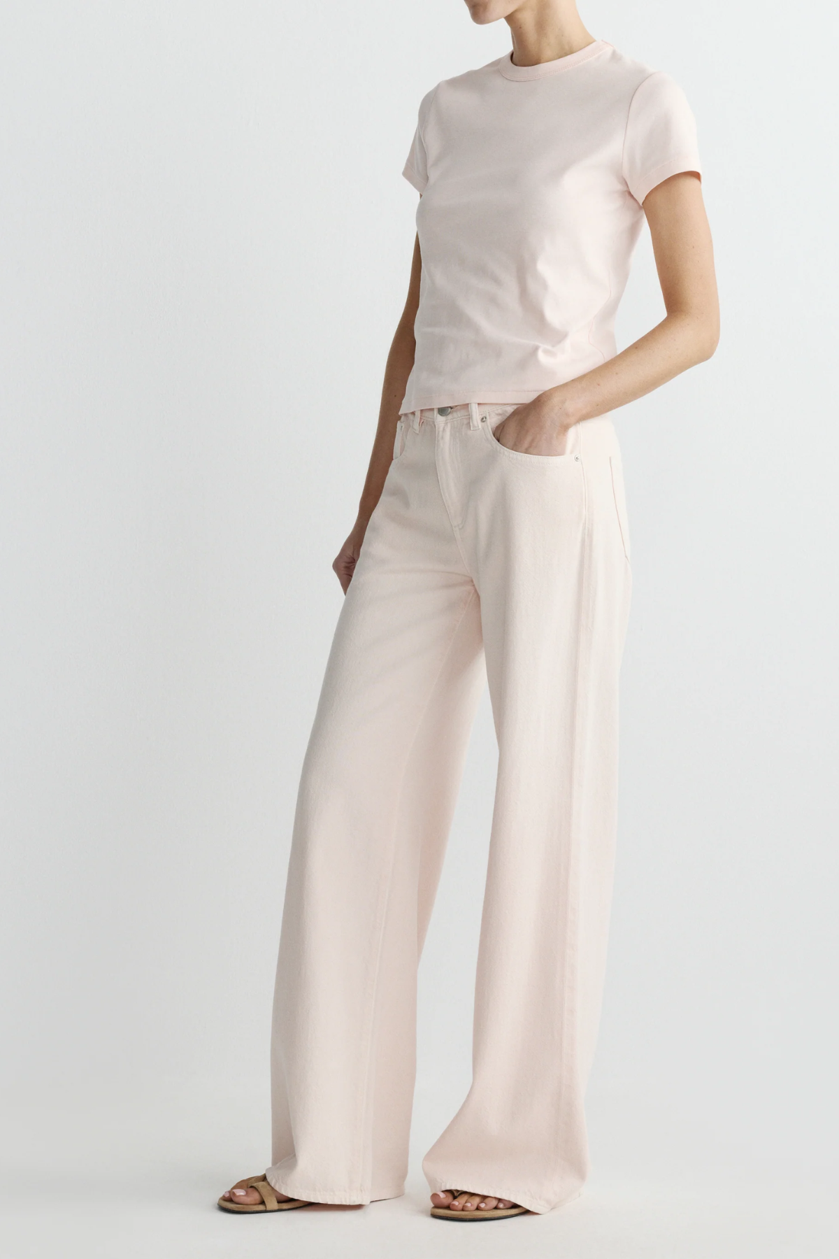 Person wearing a light pink t-shirt and wide-leg pants on a white background