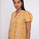 Model wearing a sleeveless orange printed blouse with a relaxed silhouette.