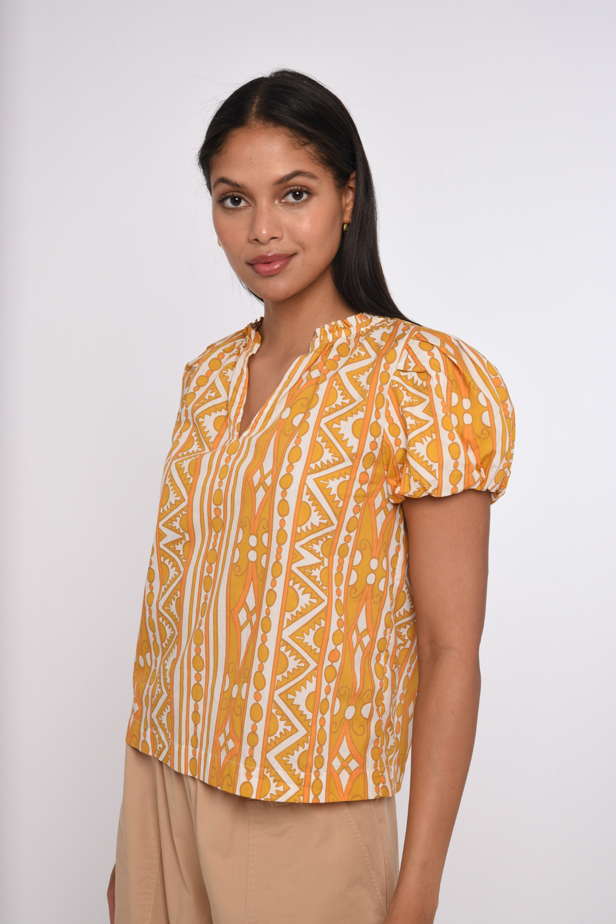 Model wearing a sleeveless orange printed blouse with a relaxed silhouette.