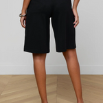 Person wearing black shorts on a wooden floor with a white wall background