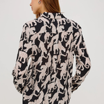 Woman wearing a black and white patterned blouse on a plain background