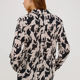 Woman wearing a black and white patterned blouse on a plain background