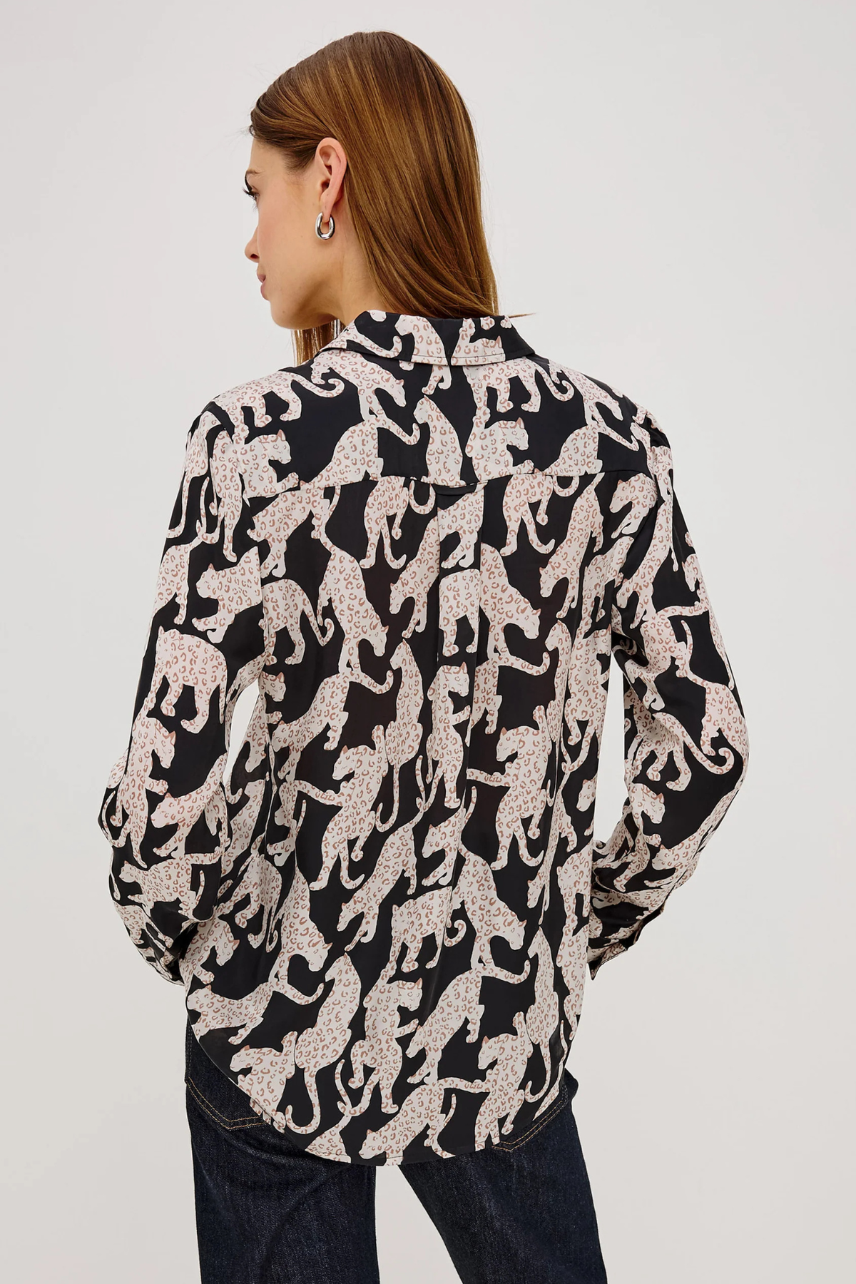 Woman wearing a black and white patterned blouse on a plain background
