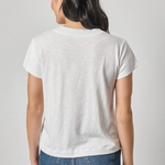 Person wearing a plain white t-shirt and blue jeans on a light gray background