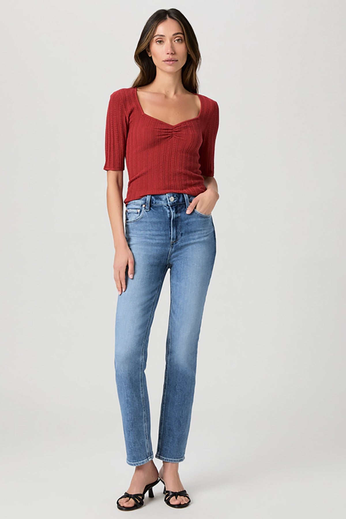 Woman wearing mid-wash straight-leg jeans with a streamlined, classic silhouette.